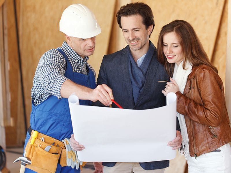 Man and woman couple talking to contractor holding plan