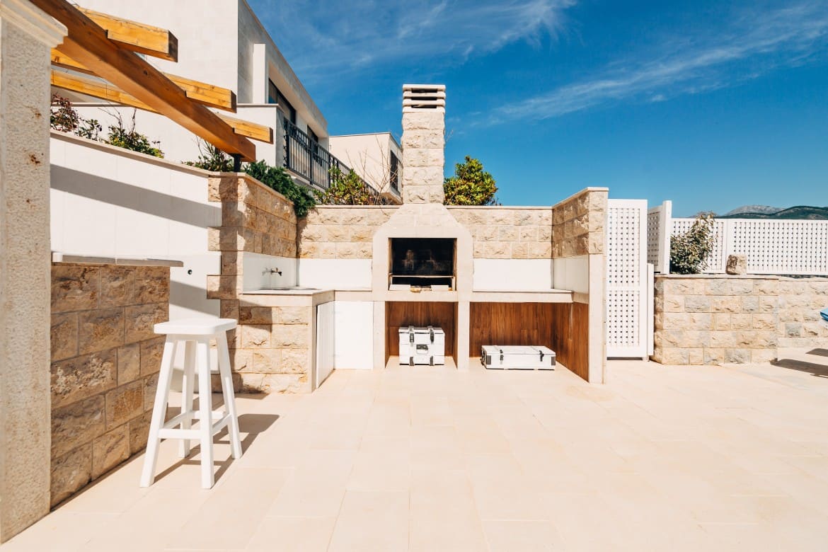 Grill area in the villa by the sea. A large courtyard with a stone grill and an open white stone kitchen.