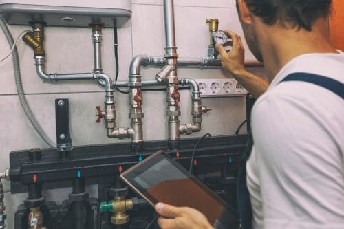 The technician checking the heating system in the boiler room with tablet in hand