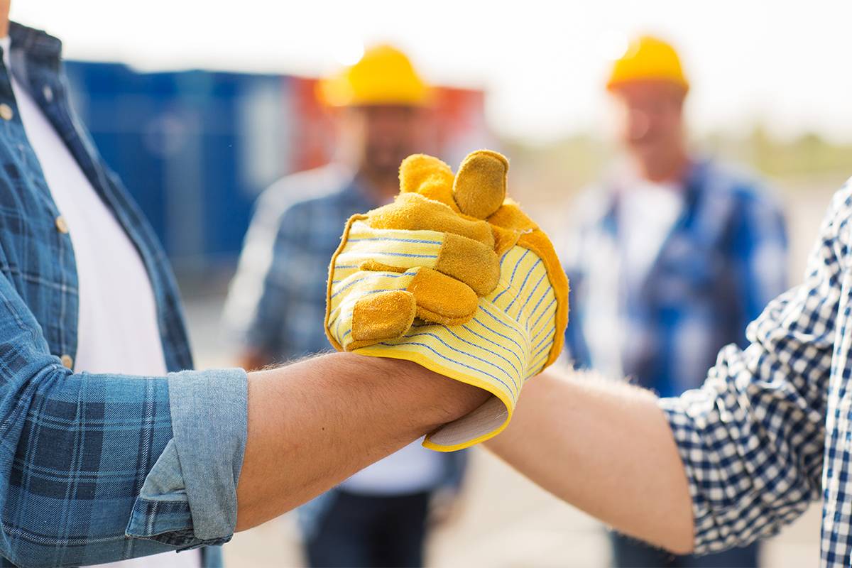 Close up of builders with gloves shaking hands