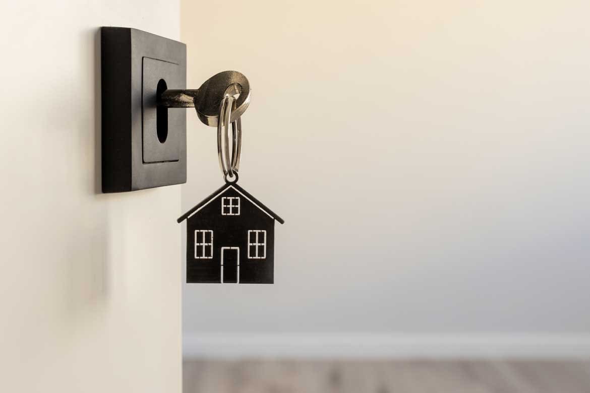 A key in a modern door lock with a house-shaped keychain, symbolizing real estate, homeownership, security, and new beginnings.
