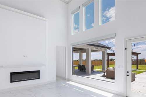 Dolcan Homes design: A bright white living room featuring a cozy fireplace and large sliding glass doors leading to an outdoor space.