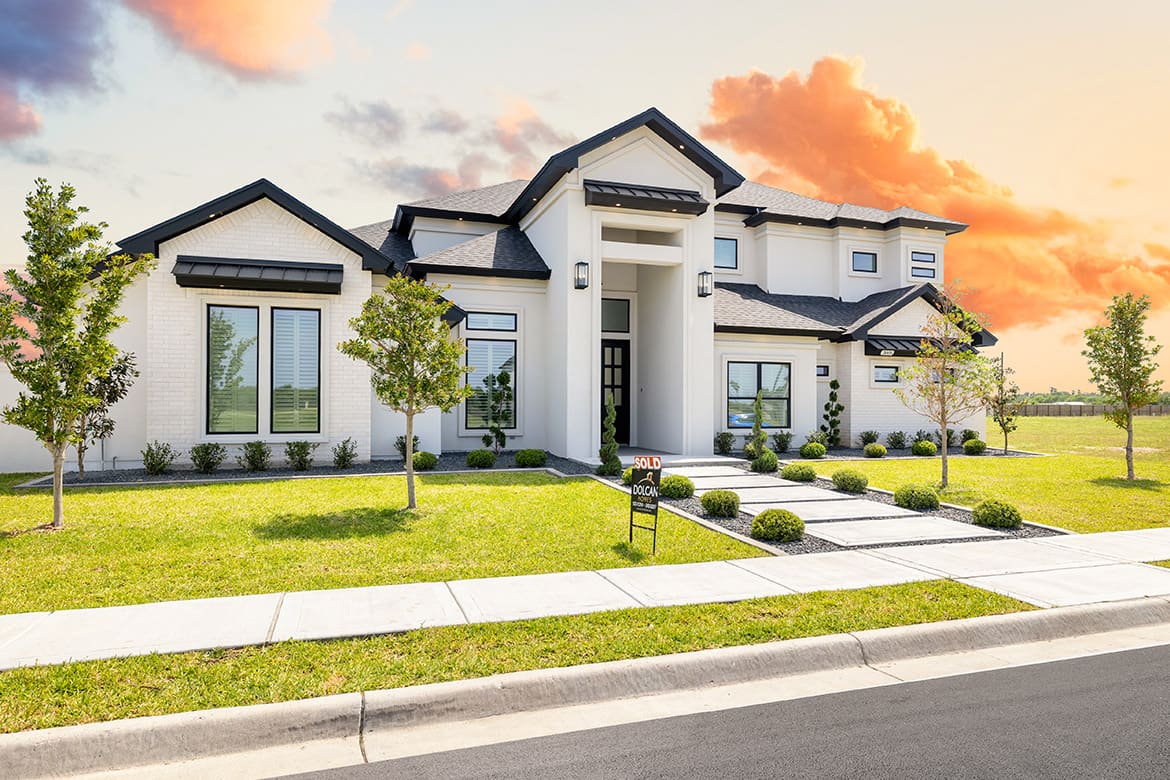 A large white house with a spacious driveway, showcasing new construction in Mission, TX.