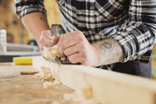 Carpenter work with plane on wood plank
