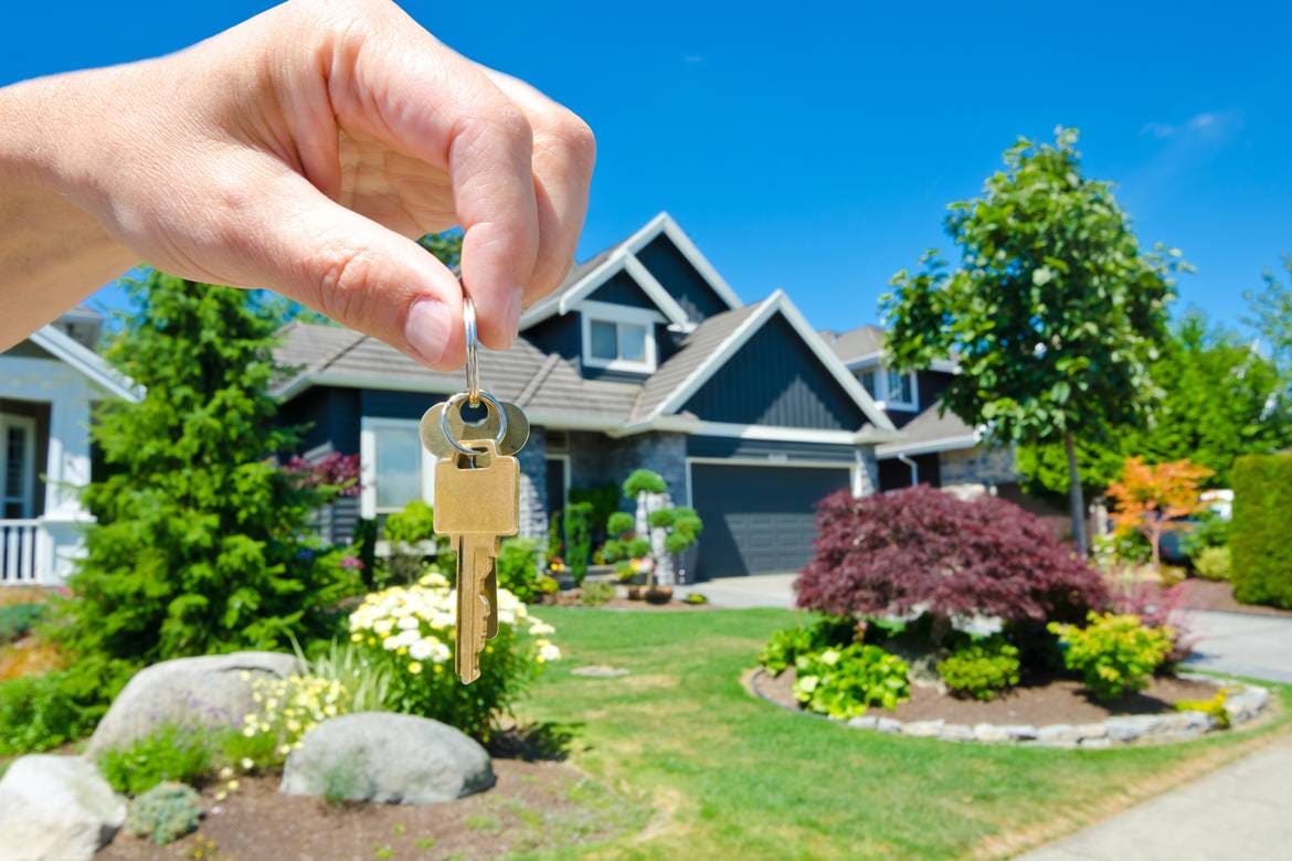Close up to hand with house keys in front of brand new home