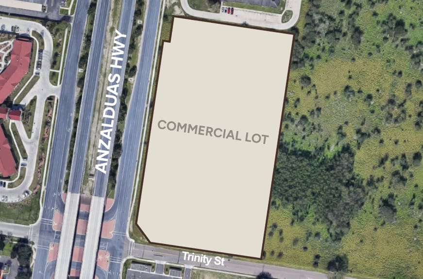 Aerial view of a vacant commercial lot bordered by Anzalduas Highway and Trinity Street, surrounded by greenery.