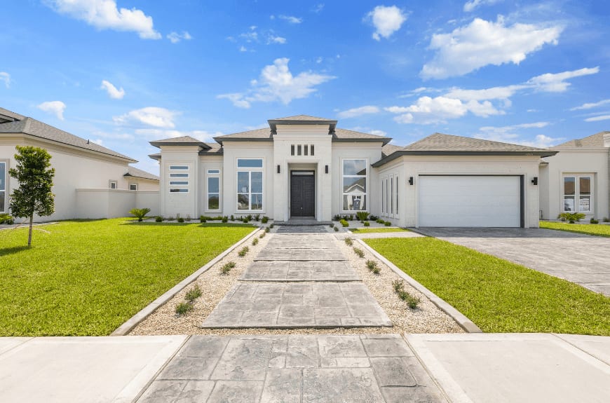 Modern single-story home exterior with a landscaped front yard and stamped concrete walkway